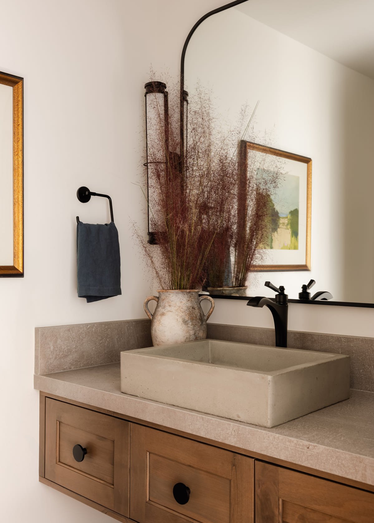Powder room with a concrete trough sink, oak vanity, and dried grasses