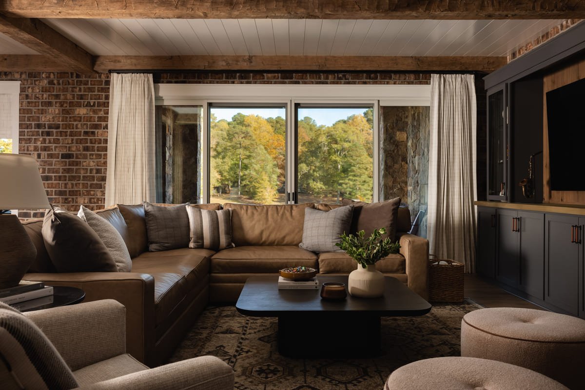 Lower level lounge with exposed brick, a deep sectional, and a black coffee table