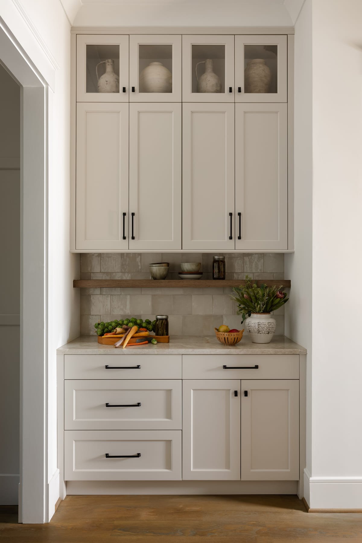 Butler pantry with glass fronted upper cabinets and stone counters