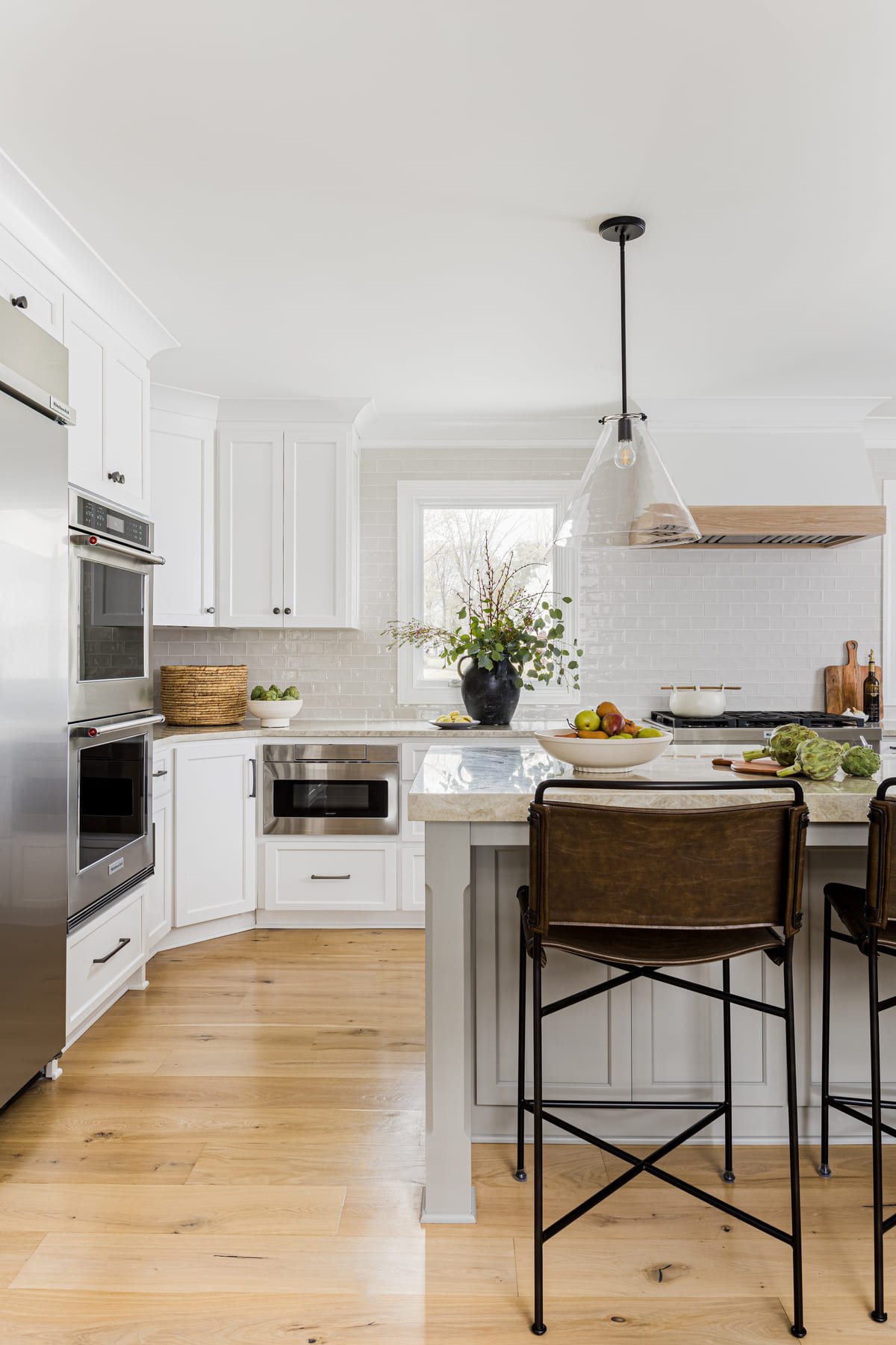 White kitchen with a wood topped island and black counter stools