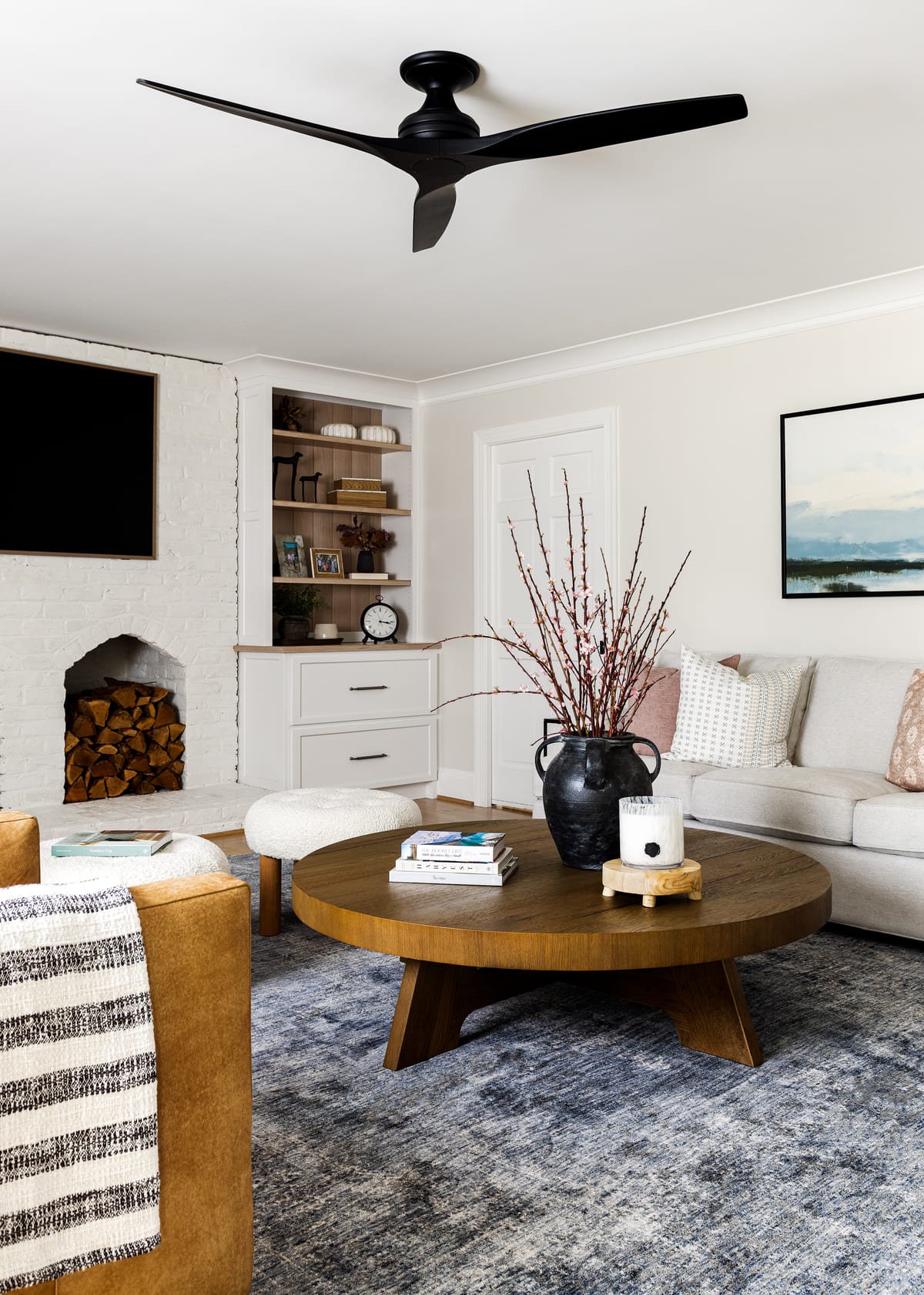 Round wood coffee table styled with a striped throw and ceramics