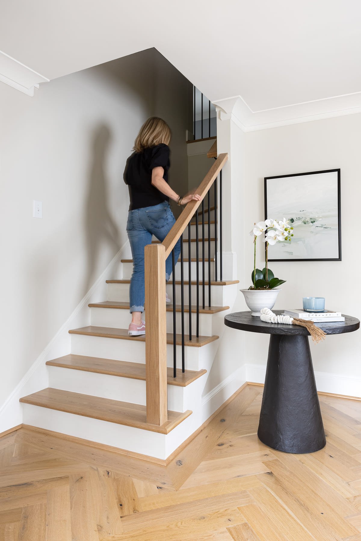 Staircase with herringbone floors and a black pedestal table