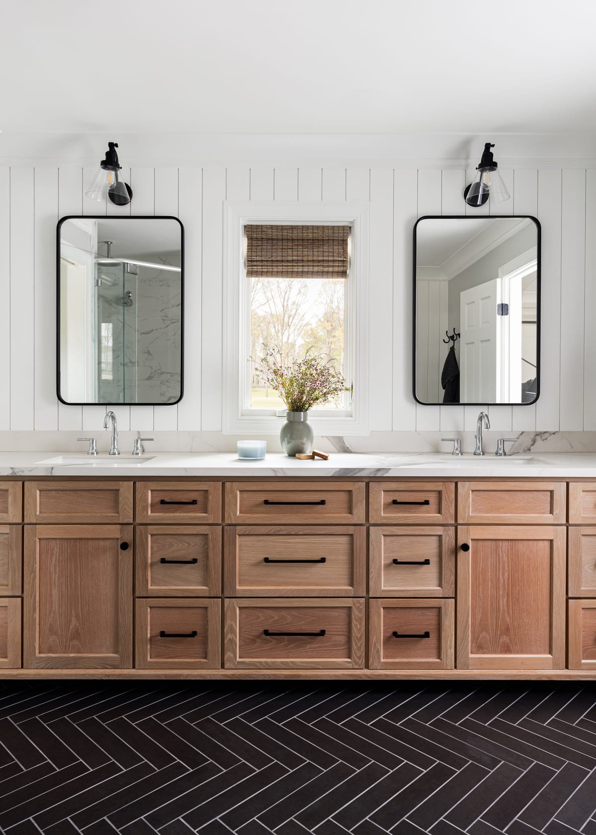 Double vanity in white oak above black herringbone tile