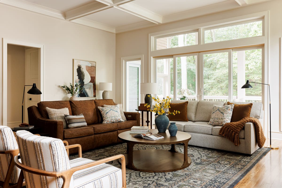 Living room with brown leather sofas, a coffered ceiling, and a bronze coffee table
