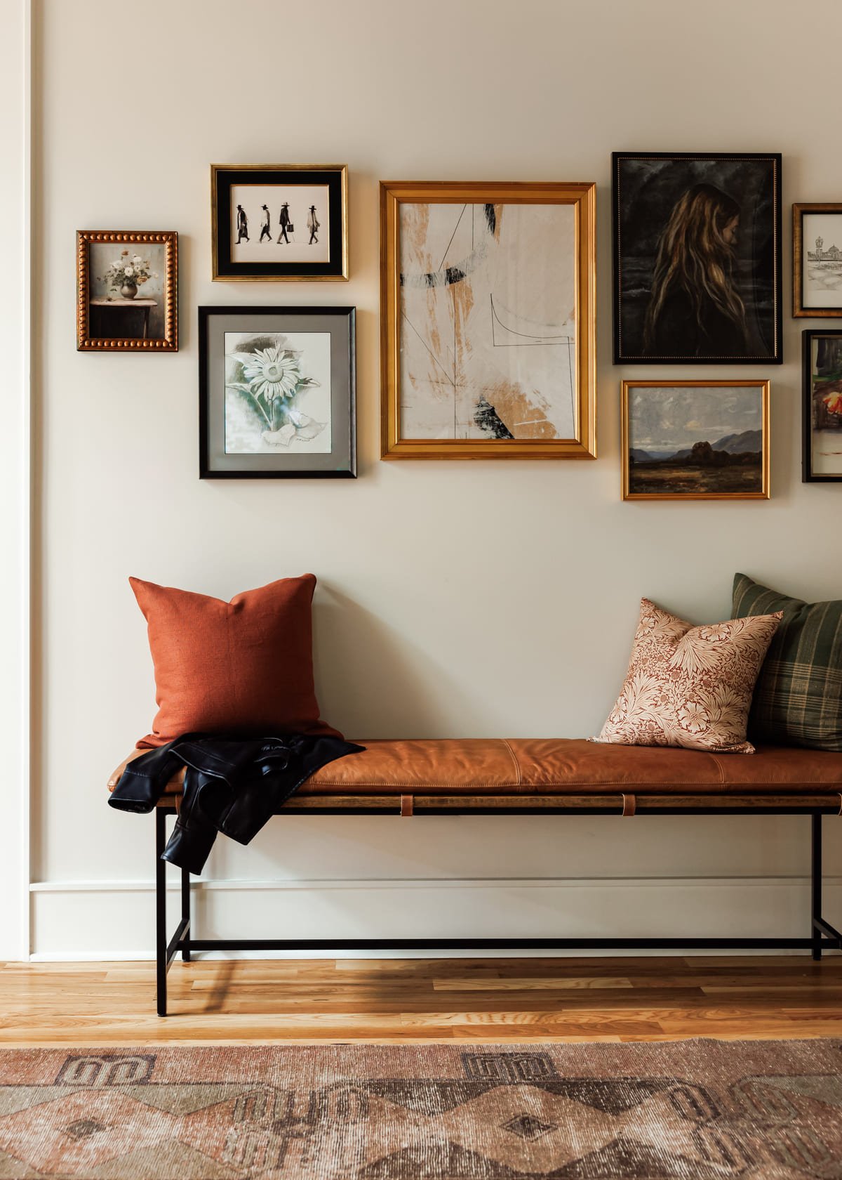 Entry bench beneath a salon style gallery wall of framed art