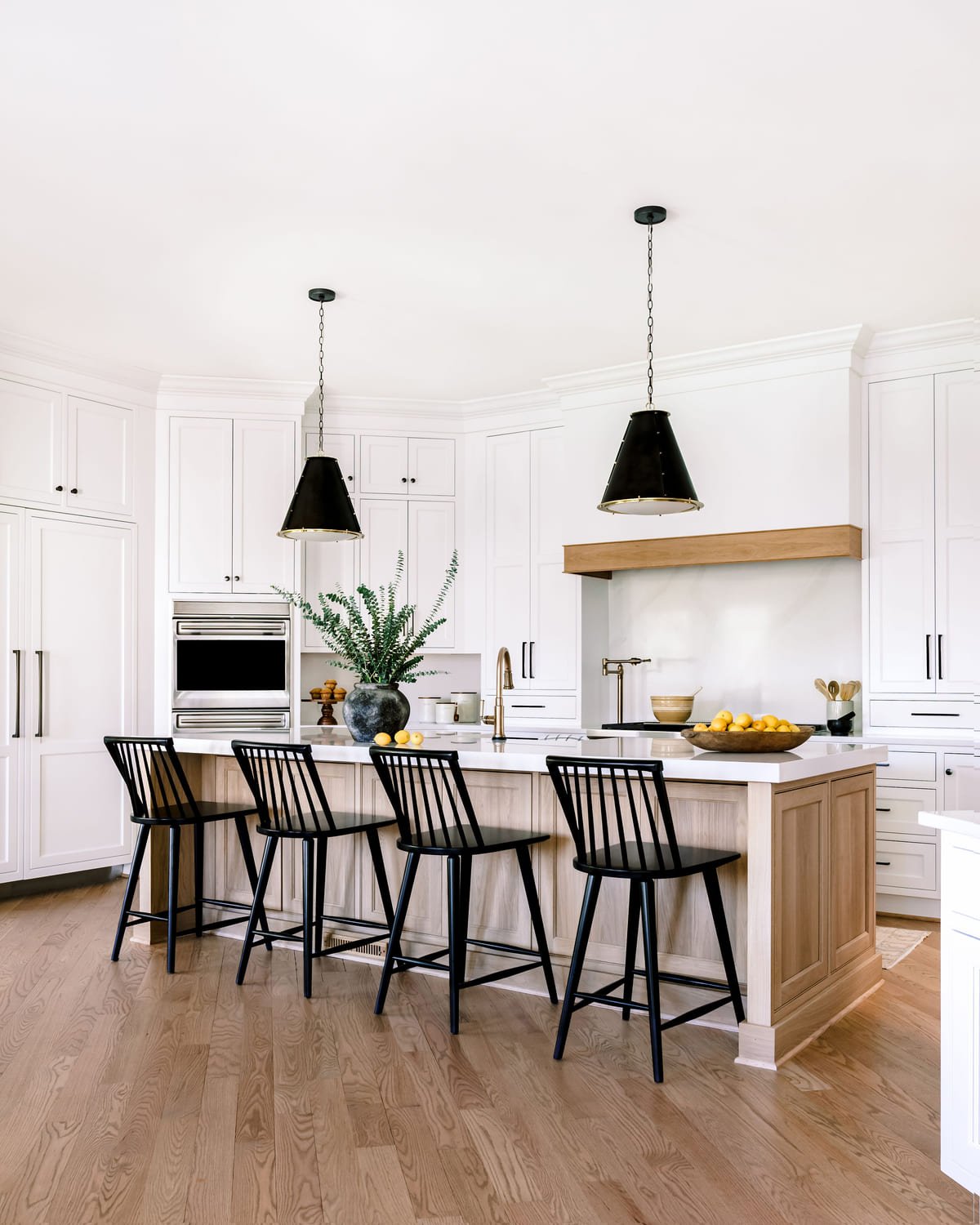 White farmhouse kitchen with black pendants and a wood topped island