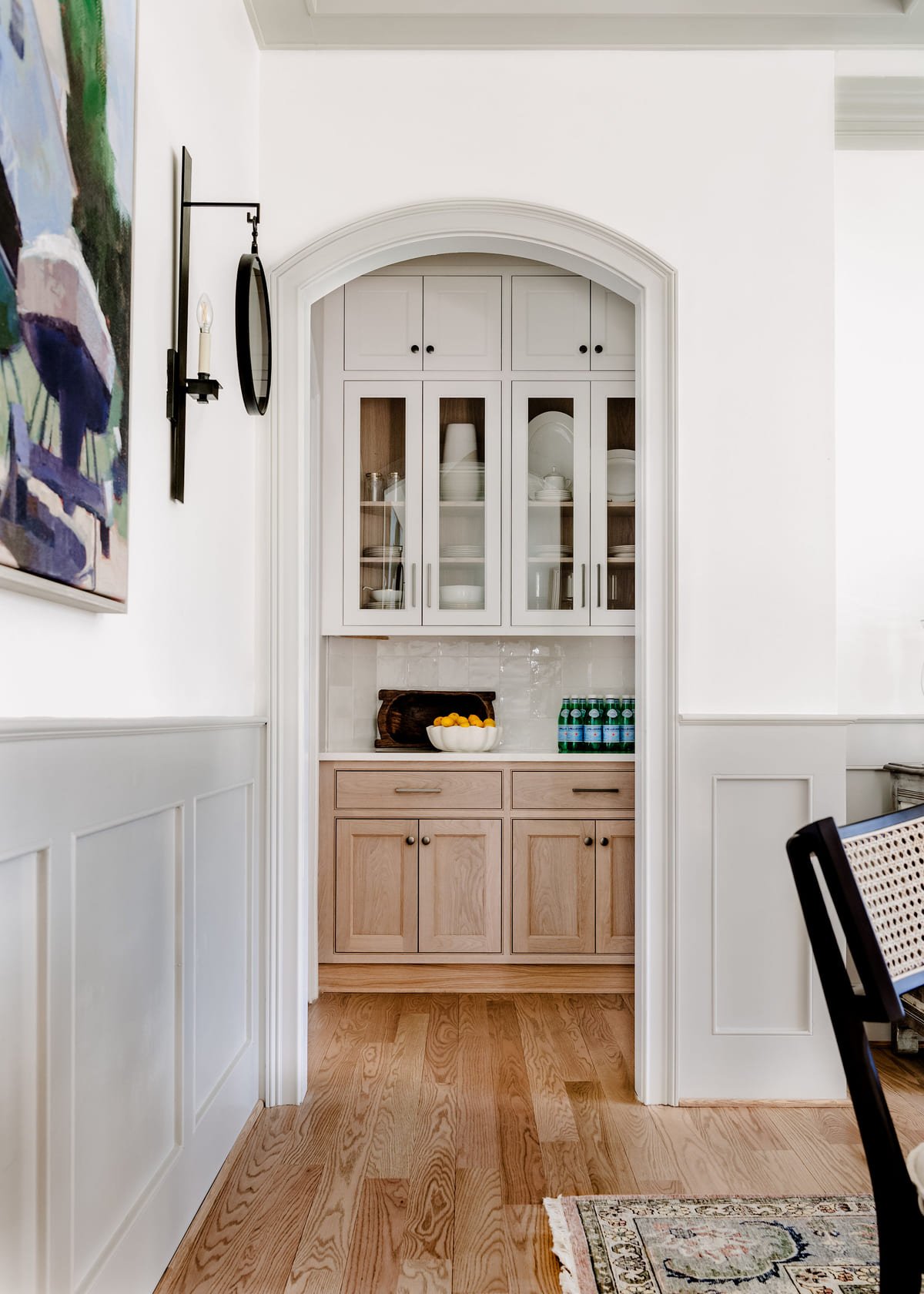 Arched pantry doorway framed by paneled wainscoting