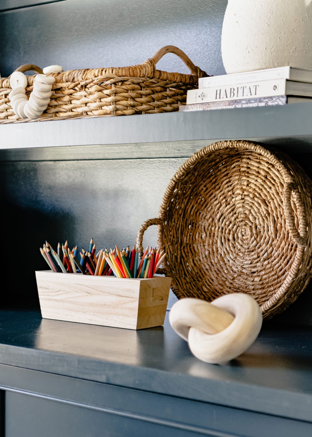 Navy shelf styled with a woven basket, books, and ceramics