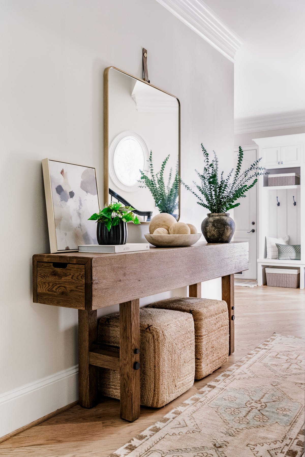 Console table with a round mirror and paired woven stools