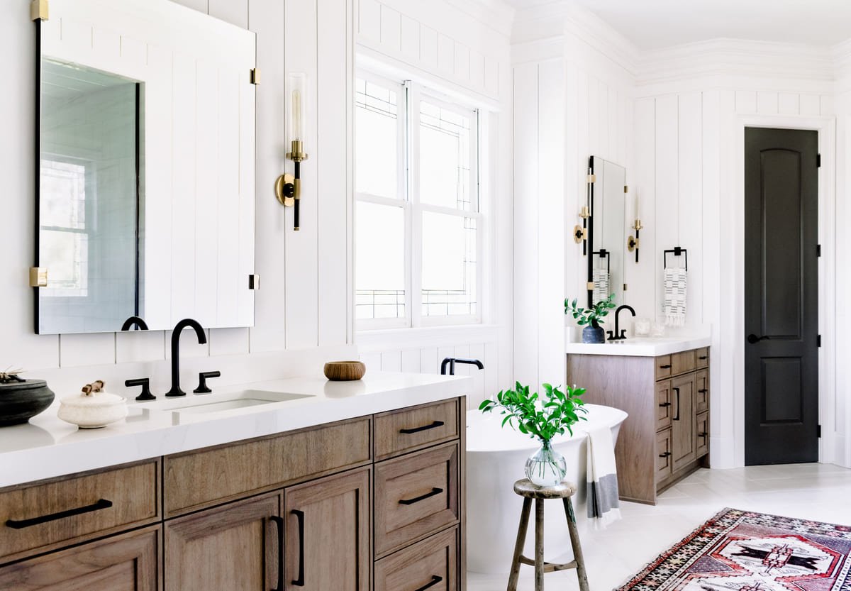Primary bath with an oak double vanity and brass sconces