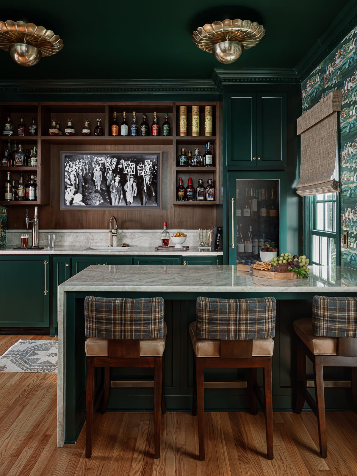 Green lacquered home bar with plaid upholstered stools and a marble counter