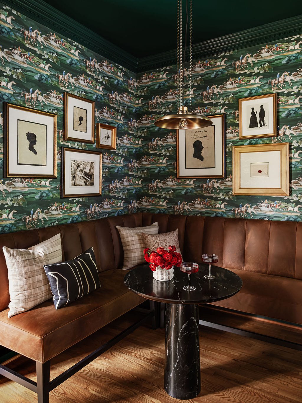 Leather banquette against equestrian toile wallpaper with a gallery of frames