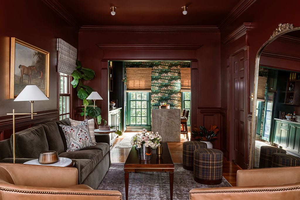 Red paneled room opening onto a stone fireplace beyond