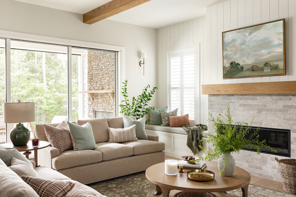 Living room with a stone fireplace, exposed beam, and landscape painting in Holly Springs
