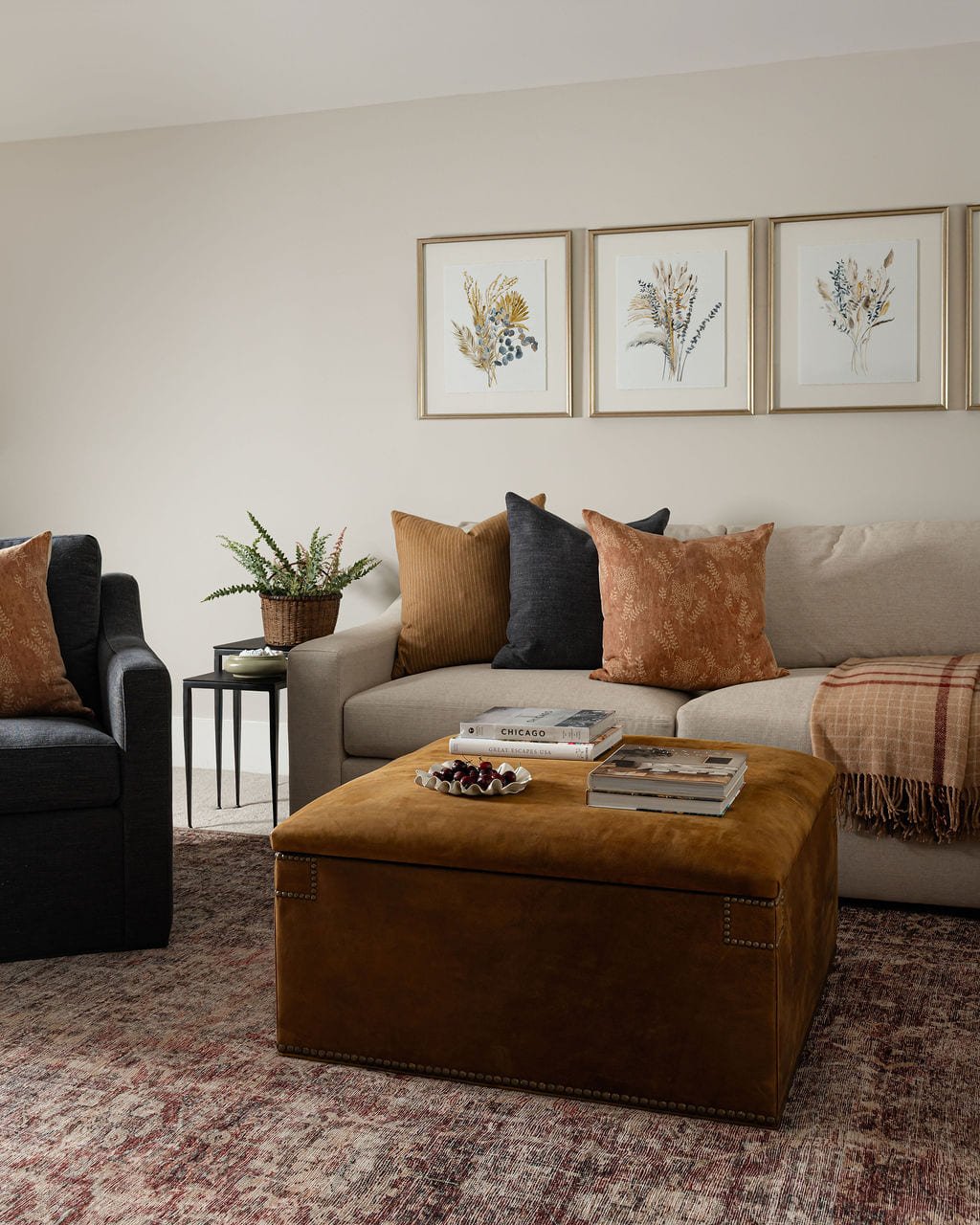 Den with a caramel leather ottoman and framed botanical prints