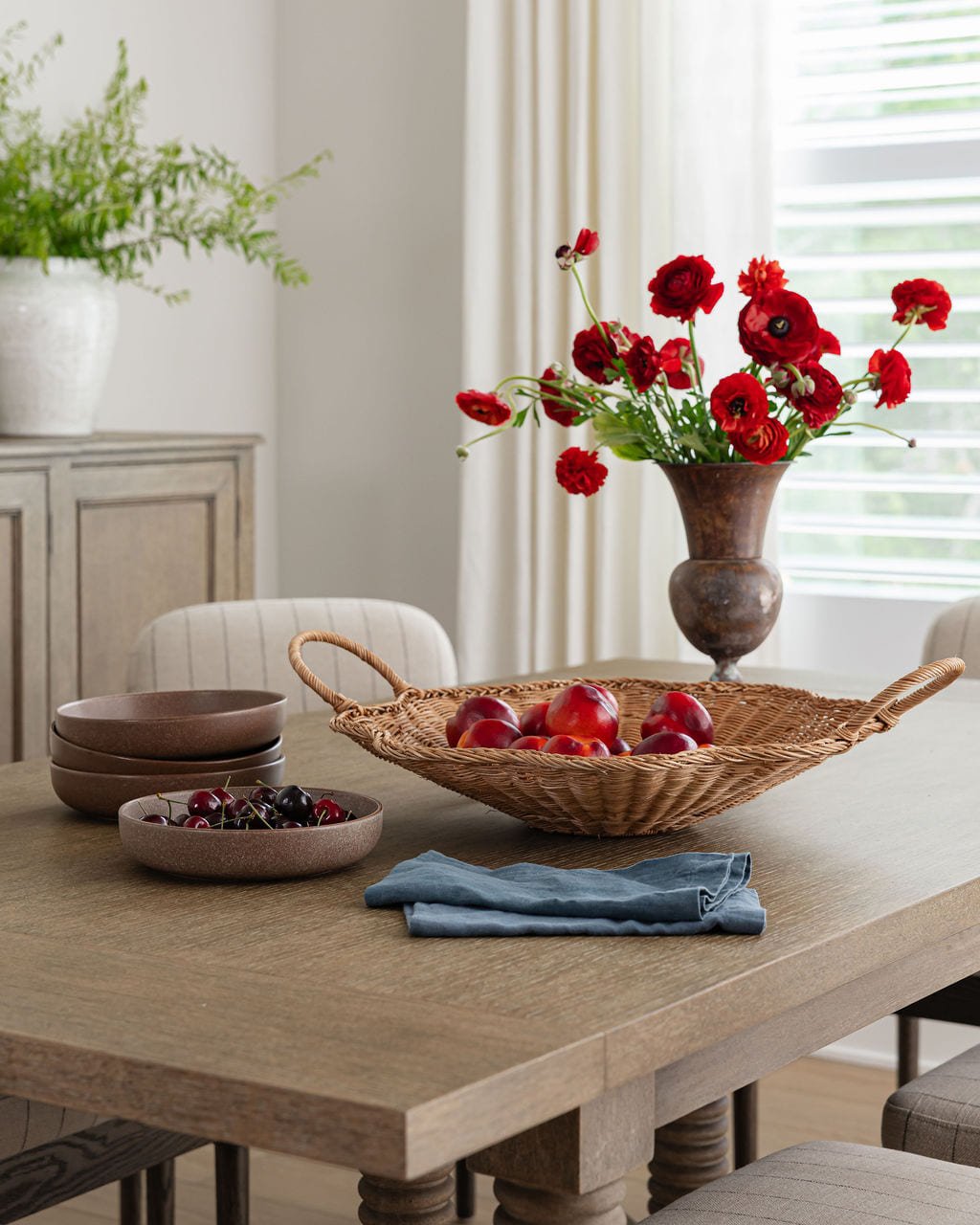 Farm table styled with red carnations and a woven fruit bowl