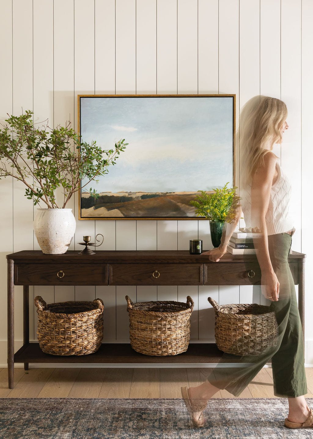 Console table styled with a landscape painting and woven baskets