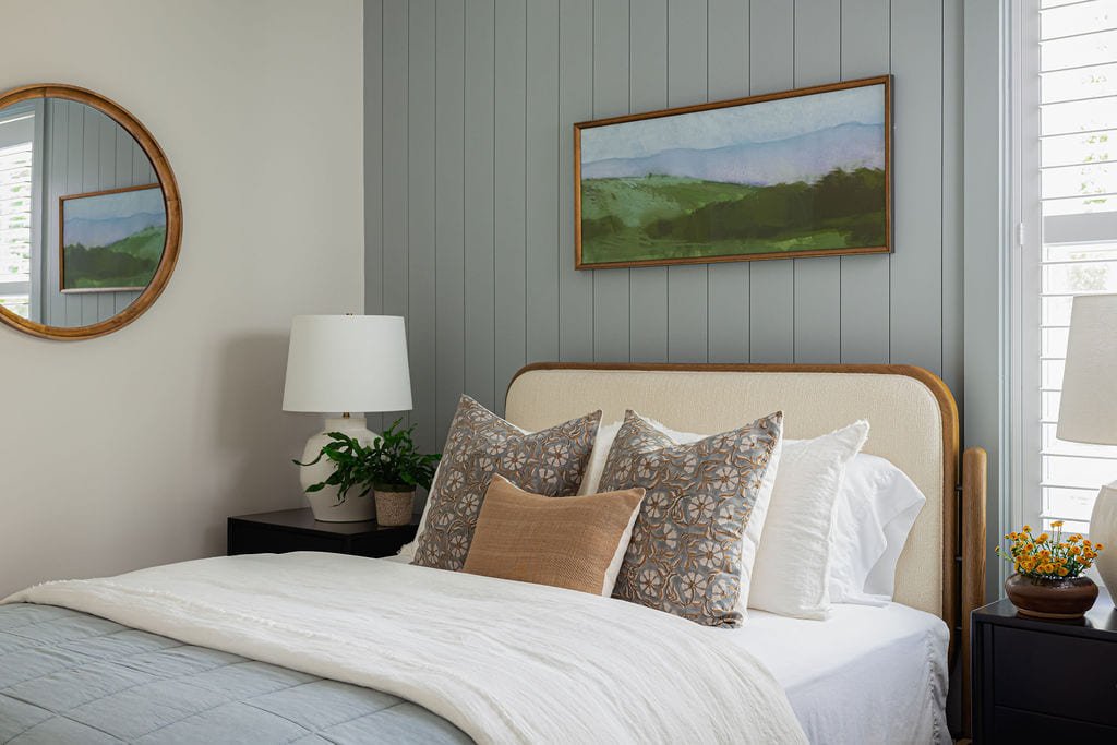 Guest bedroom with a cane headboard against blue green paneling