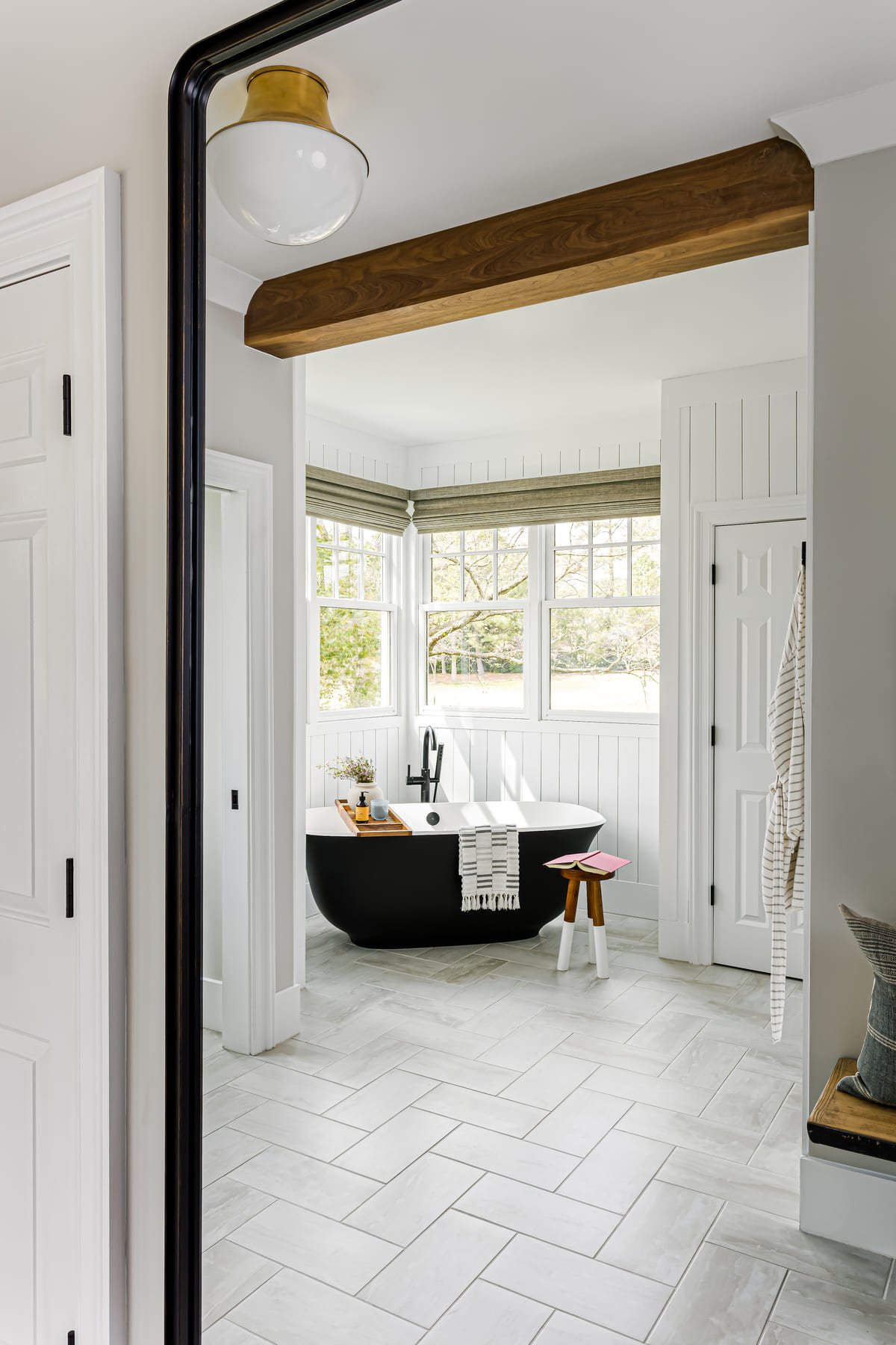 View through a bedroom doorway to a freestanding tub beneath a beam