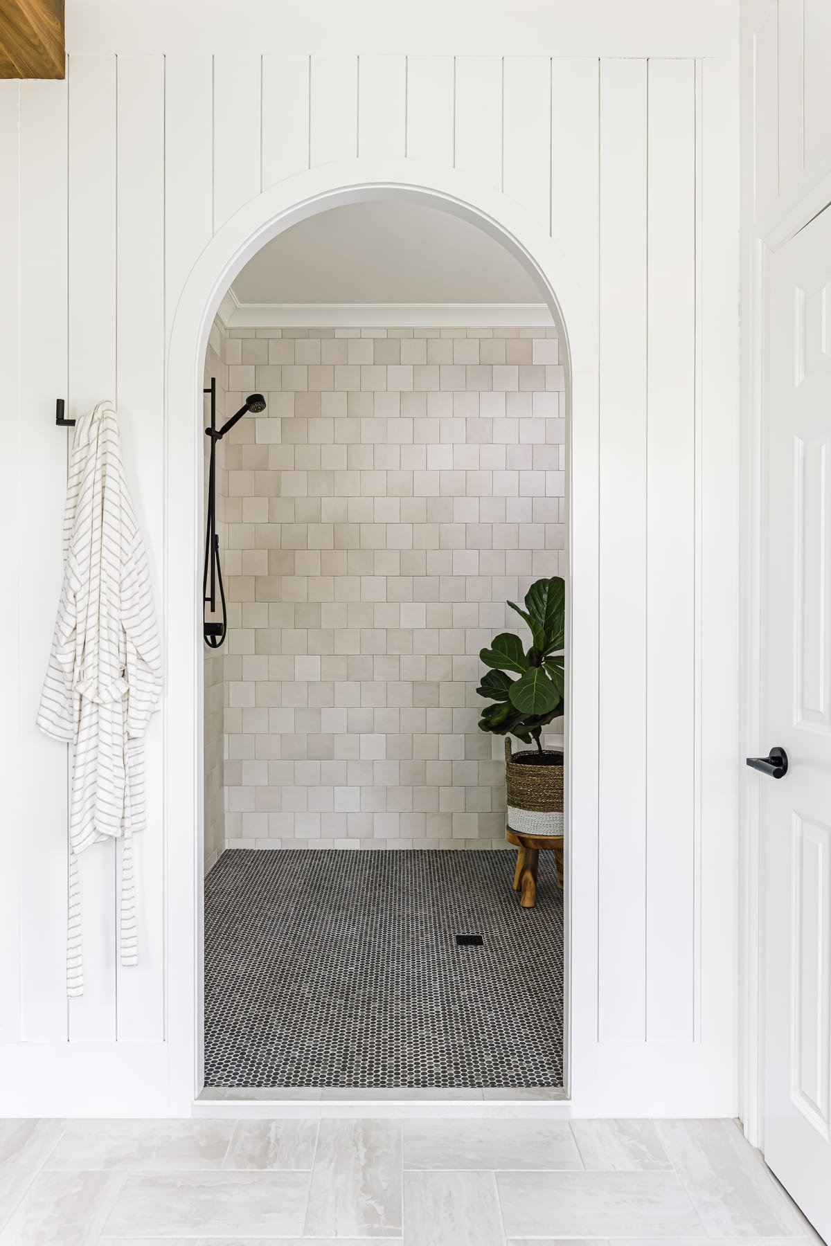 Arched walk in shower framed by vertical shiplap paneling