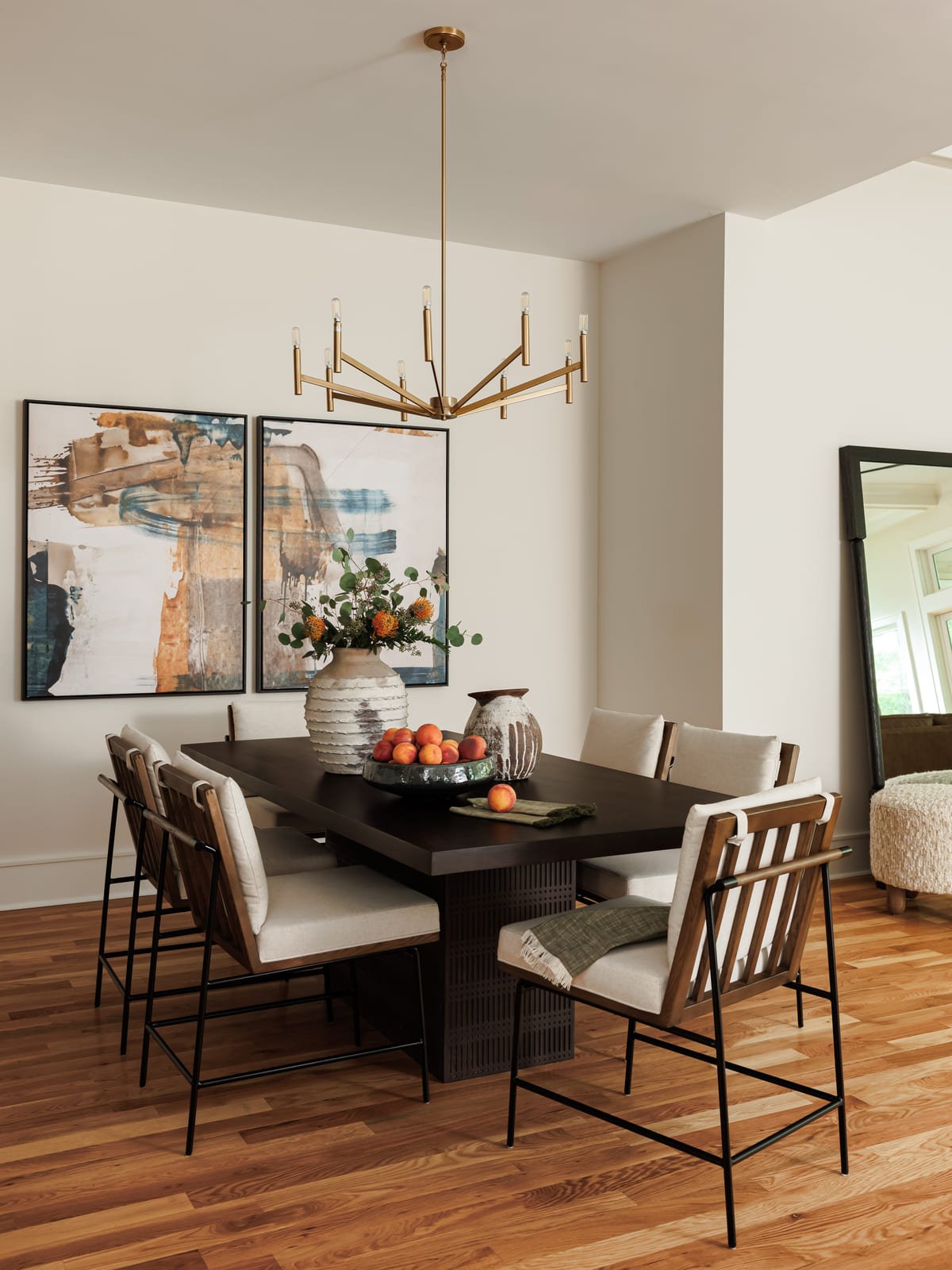 Dining room with a black oval table beneath a branching brass chandelier