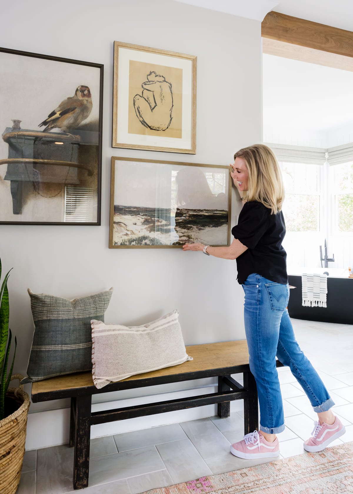 Designer hanging framed art above a bench during a furnishing installation