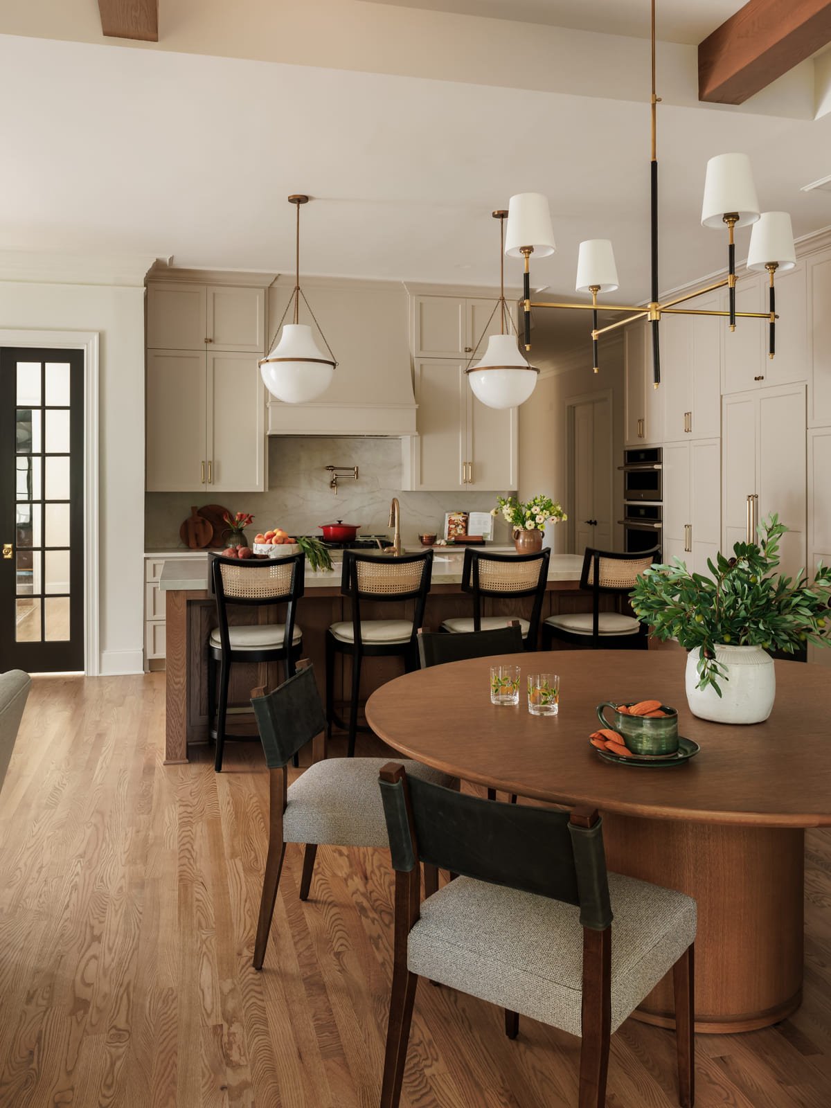 Oval breakfast table under an alabaster pendant beside black doors