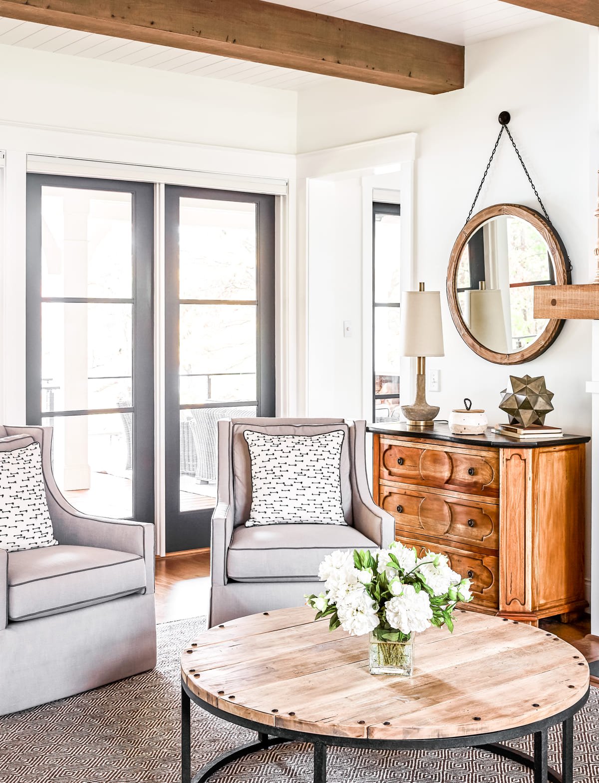 Sitting area with a round wood table, antique chest, and arched mirror
