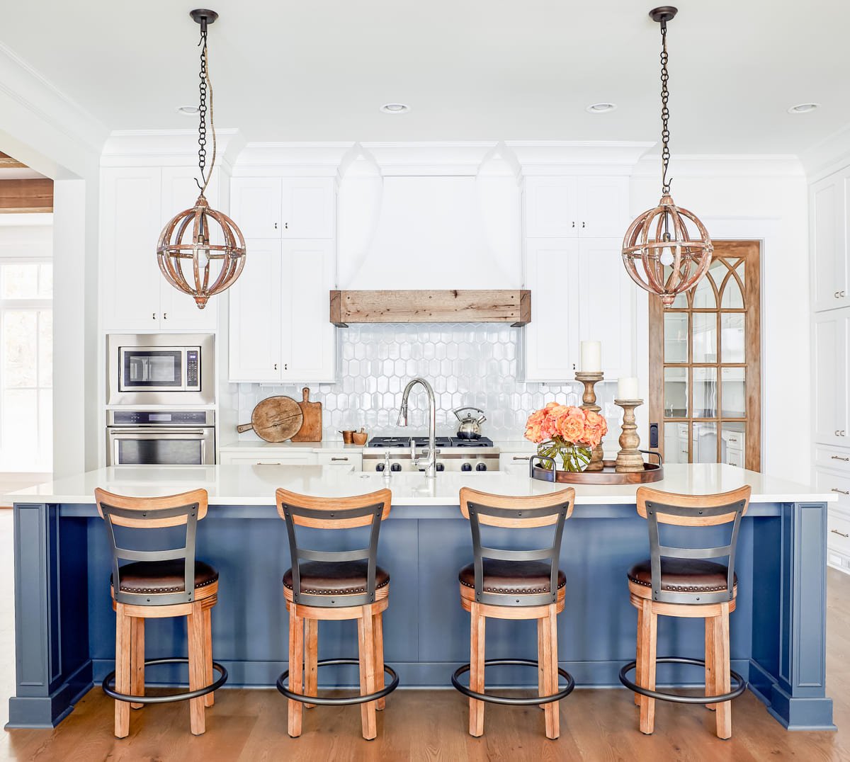 Blue kitchen island with orb pendants and wood counter stools