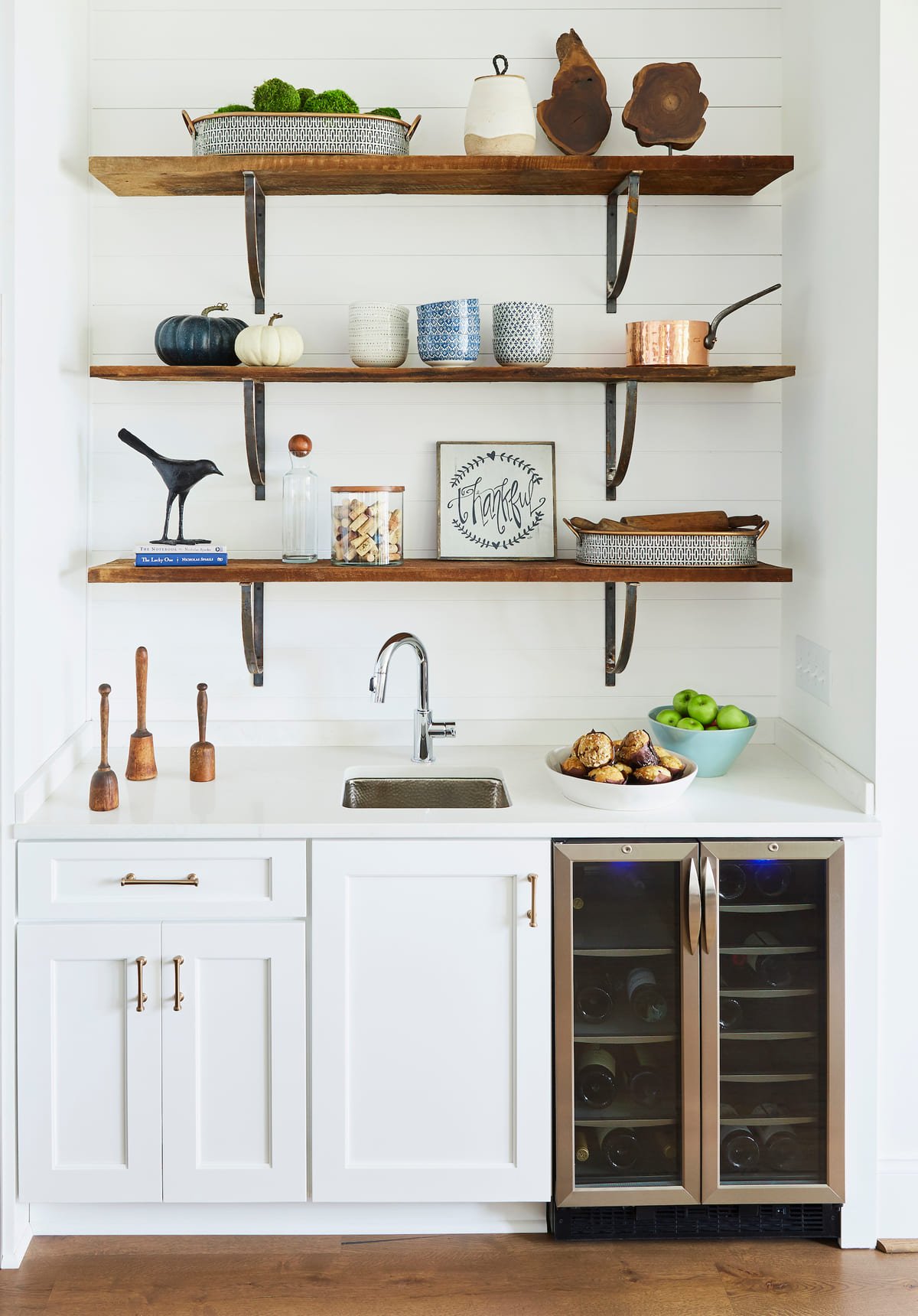 Home bar with walnut floating shelves and a beverage fridge
