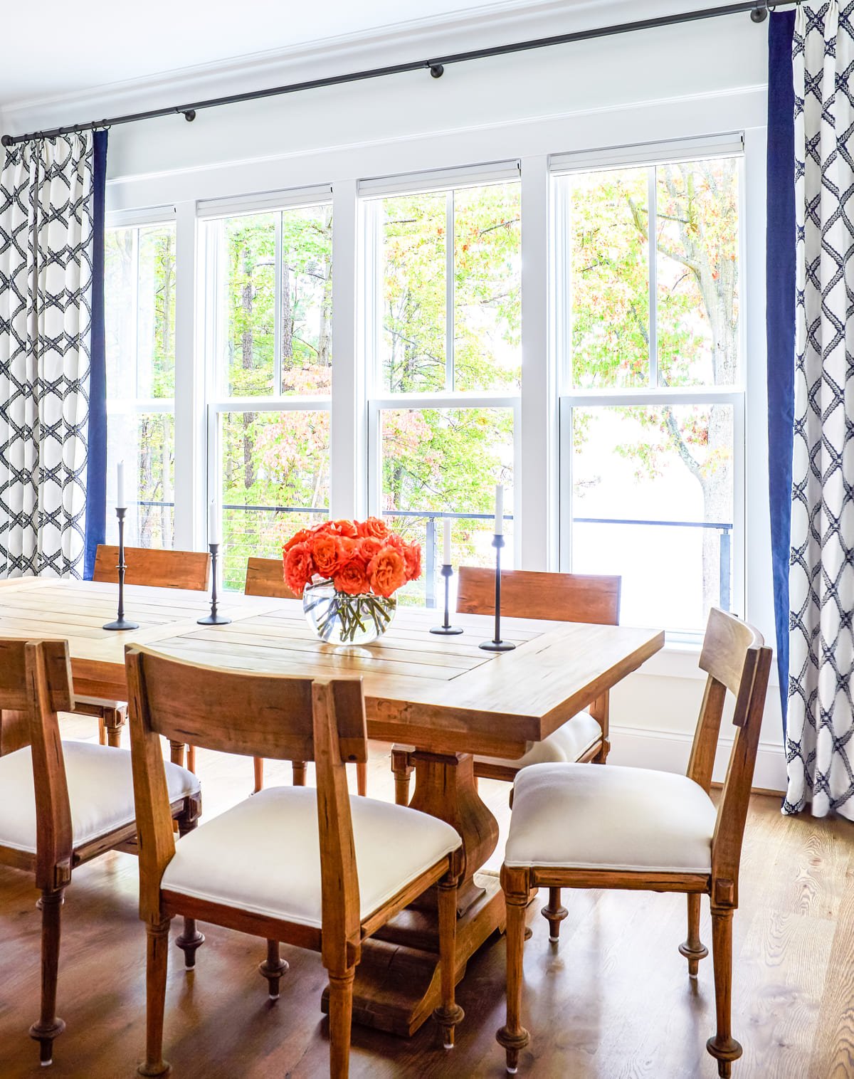 Dining table set with orange blooms against blue patterned drapery