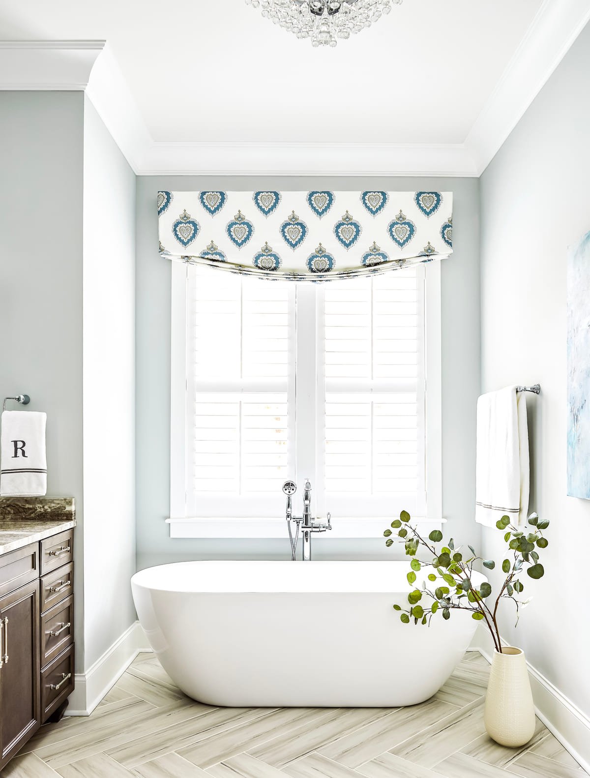 Freestanding soaking tub beneath a patterned window valance
