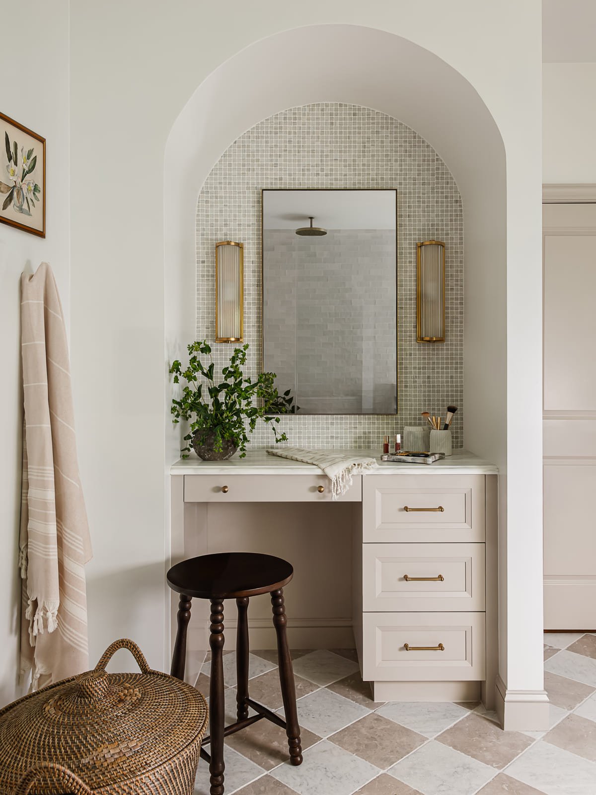 Arched vanity alcove with checkered stone floor and brass sconces in a Raleigh primary suite