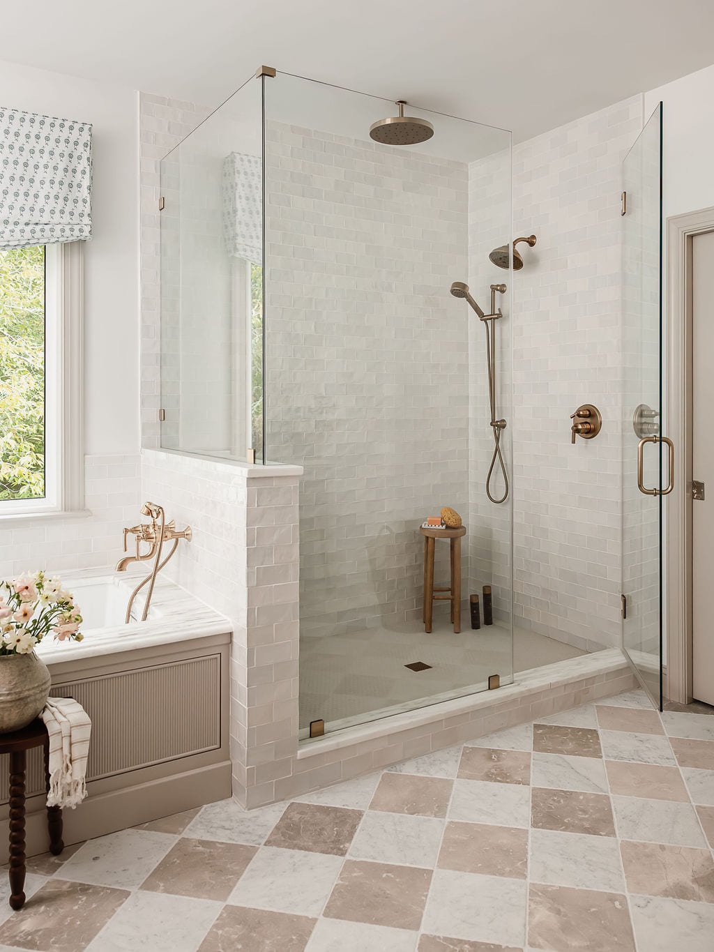 Walk in shower with marble tile, brass fittings, and a checkered stone floor