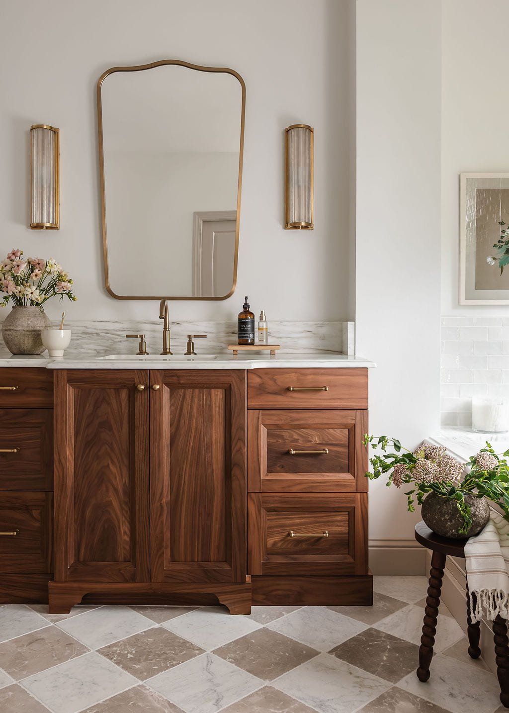 Walnut vanity with an arched mirror and layered brass lighting