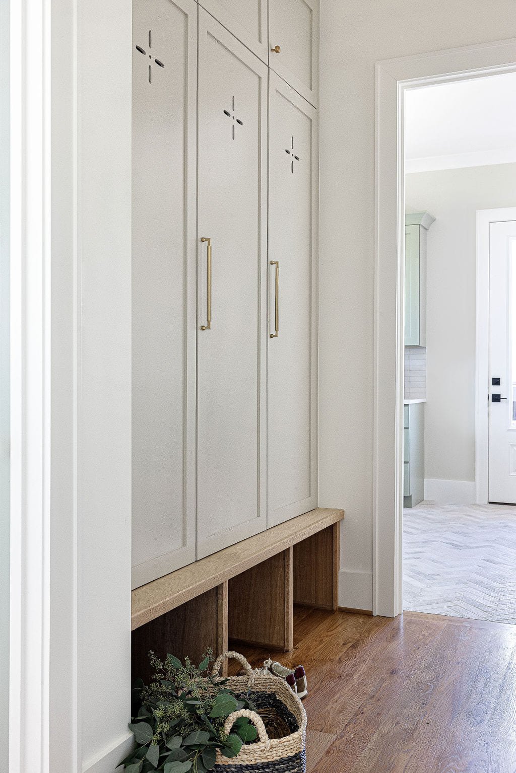 Mudroom with tall lockers, a built in bench, and warm wood floors
