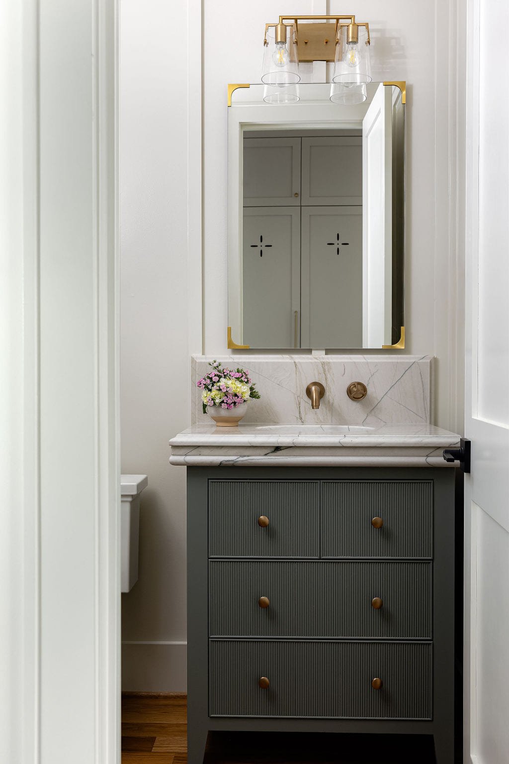 Powder room with a green vanity and a brass framed mirror