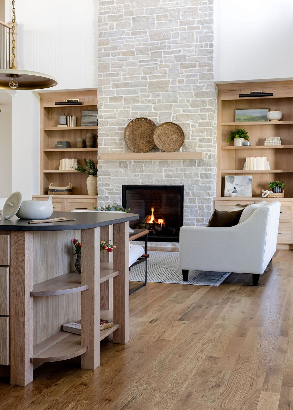 Living room with a whitewashed brick fireplace and flanking shelves