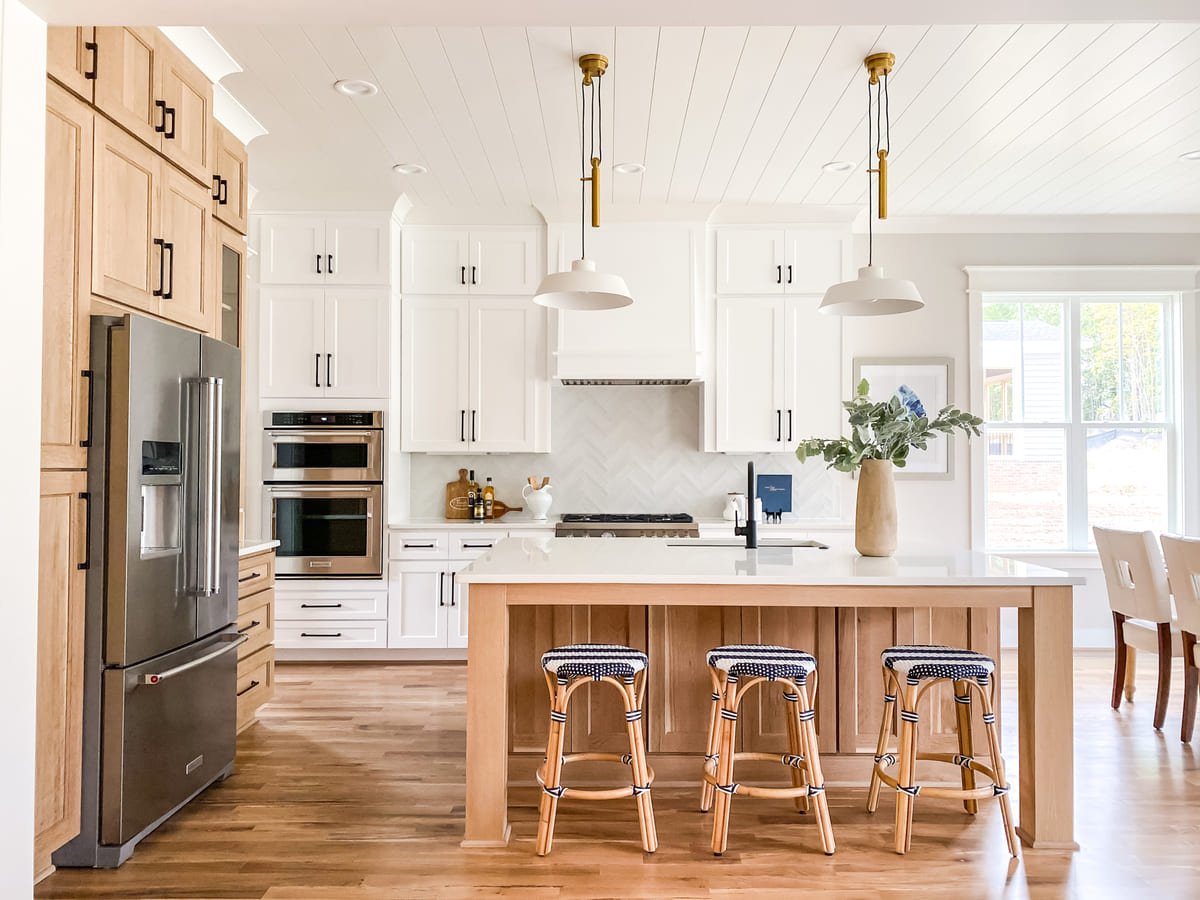White kitchen with an oak island and woven counter stools