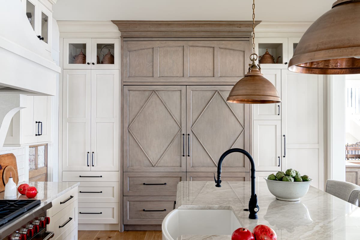Gray oak kitchen with copper pendants and a farmhouse sink