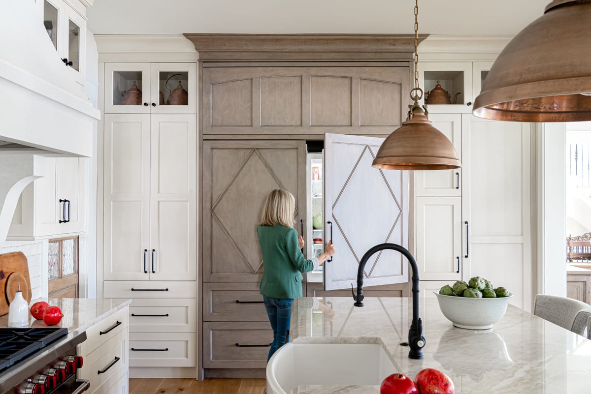 Designer at the kitchen sink beneath copper pendant lighting