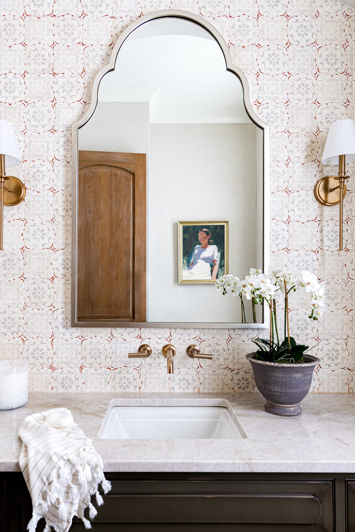 Powder room with a wood framed mirror, orchid, and brass wall taps