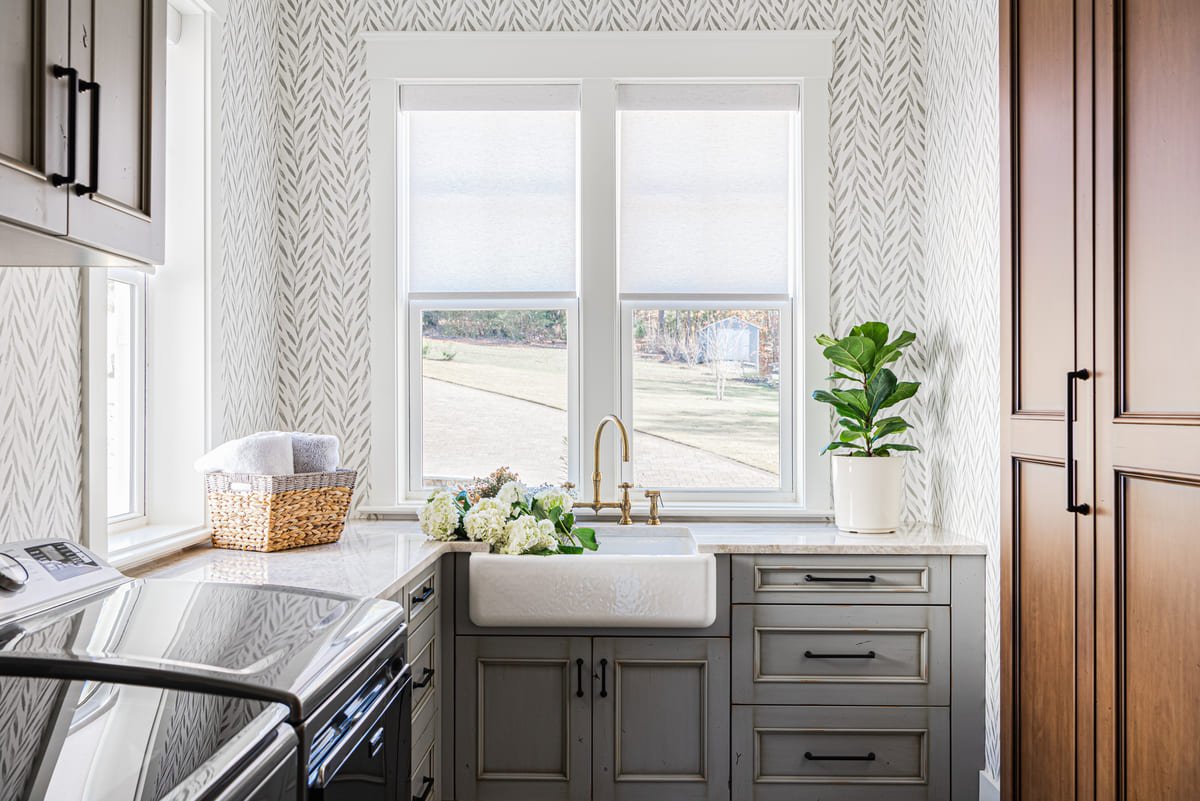 Scullery with a farmhouse sink beneath a window and wood cabinetry