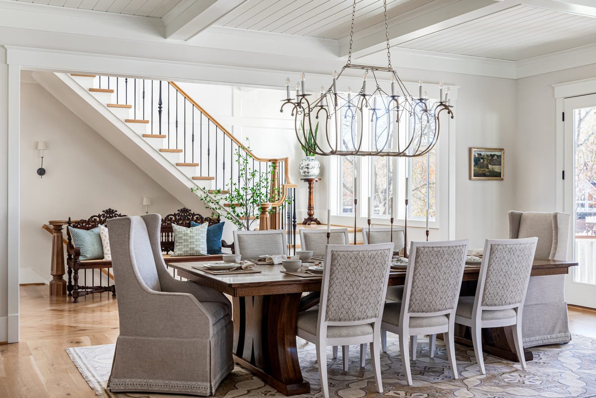 Dining room under an orb chandelier with upholstered host chairs